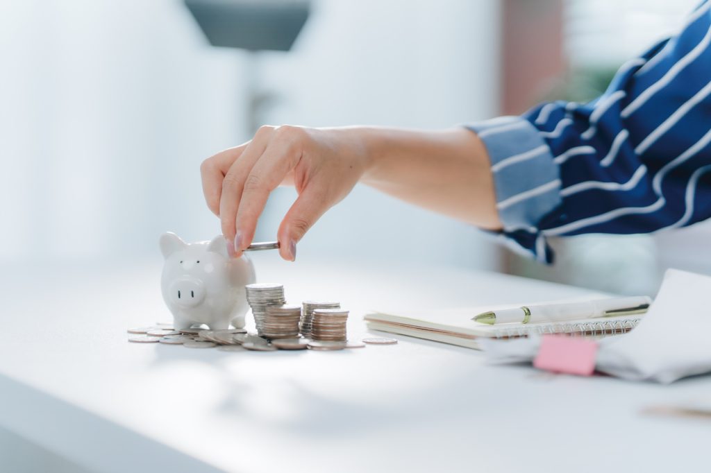 Pessoa colocando moeda em cofrinho, simbolizando economia e planejamento financeiro para clínicas médicas