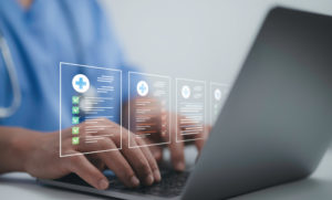 Agendamento online: como ter uma clínica de destaque 2 Recepcionista de clínica usando o seu notebook com um holograma de funções do software de gestão