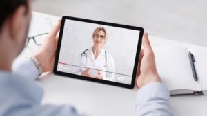Como investir em anúncios em marketing médico? 1 Homem assistindo a um vídeo médico de uma doutora em um tablet