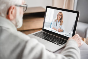 Idoso usando um notebook para fazer uma teleconsulta com um médico