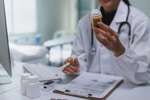 Receita amarela: como preencher e evitar erros na prescrição 1 Médico segurando frasco de medicamento enquanto revisa informações de prescrição