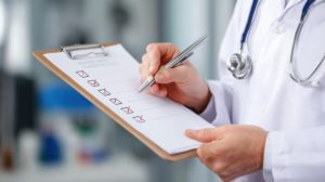 Como delegar funções administrativas sem perder qualidade no atendimento 1 Médico marcando as funções administrativas em uma prancheta