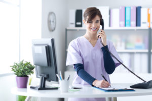 Secretária virtual ou atendente humano? Como equilibrar no seu consultório 1 Recepcionista de uma clínica médica atendendo um telefone