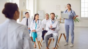 Como reduzir custos operacionais sem perder qualidade no atendimento médico 1 Equipe do consultório médico sentada em cadeira participando de um treinamento