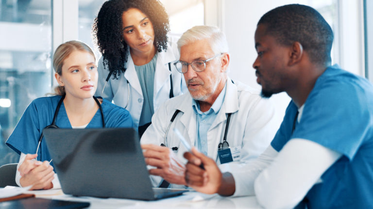 Reunião de médicos e funcionários em volta de um computador