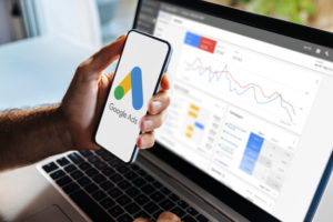 Google Ads para médicos: guia para campanhas de baixo custo e alta conversão 1 Médico segurando um celular na frente da tela do computador com o Google Ads aberto